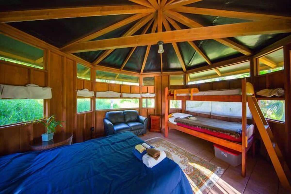 Une cabane en bois avec un lit superposé, un canapé et un bureau.