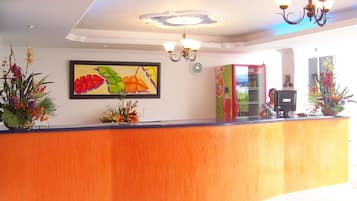 A reception area with a wooden reception desk, a framed floral artwork, and a Coca-Cola refrigerator.