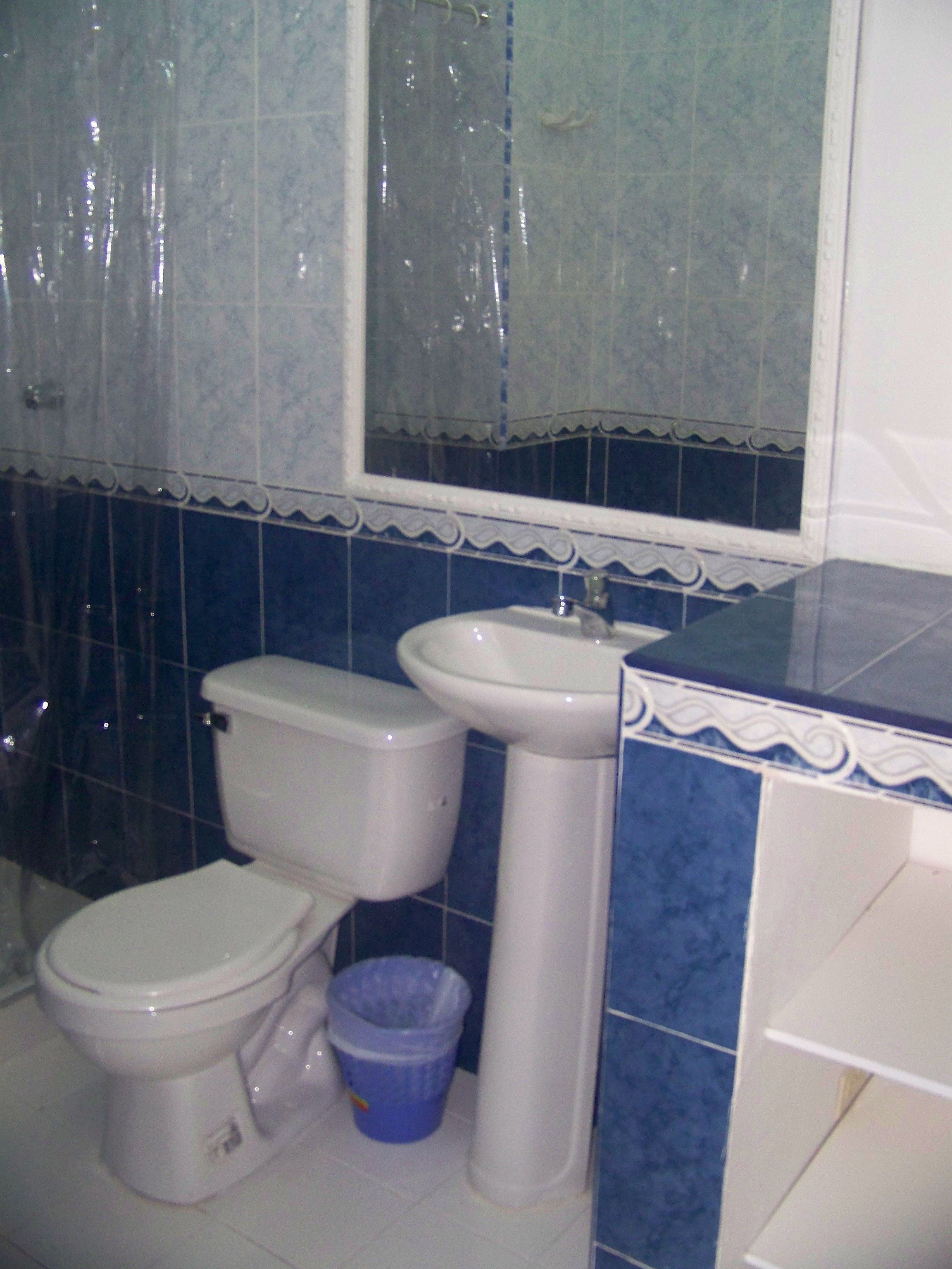 A bathroom with a toilet, sink, and blue-tiled walls.