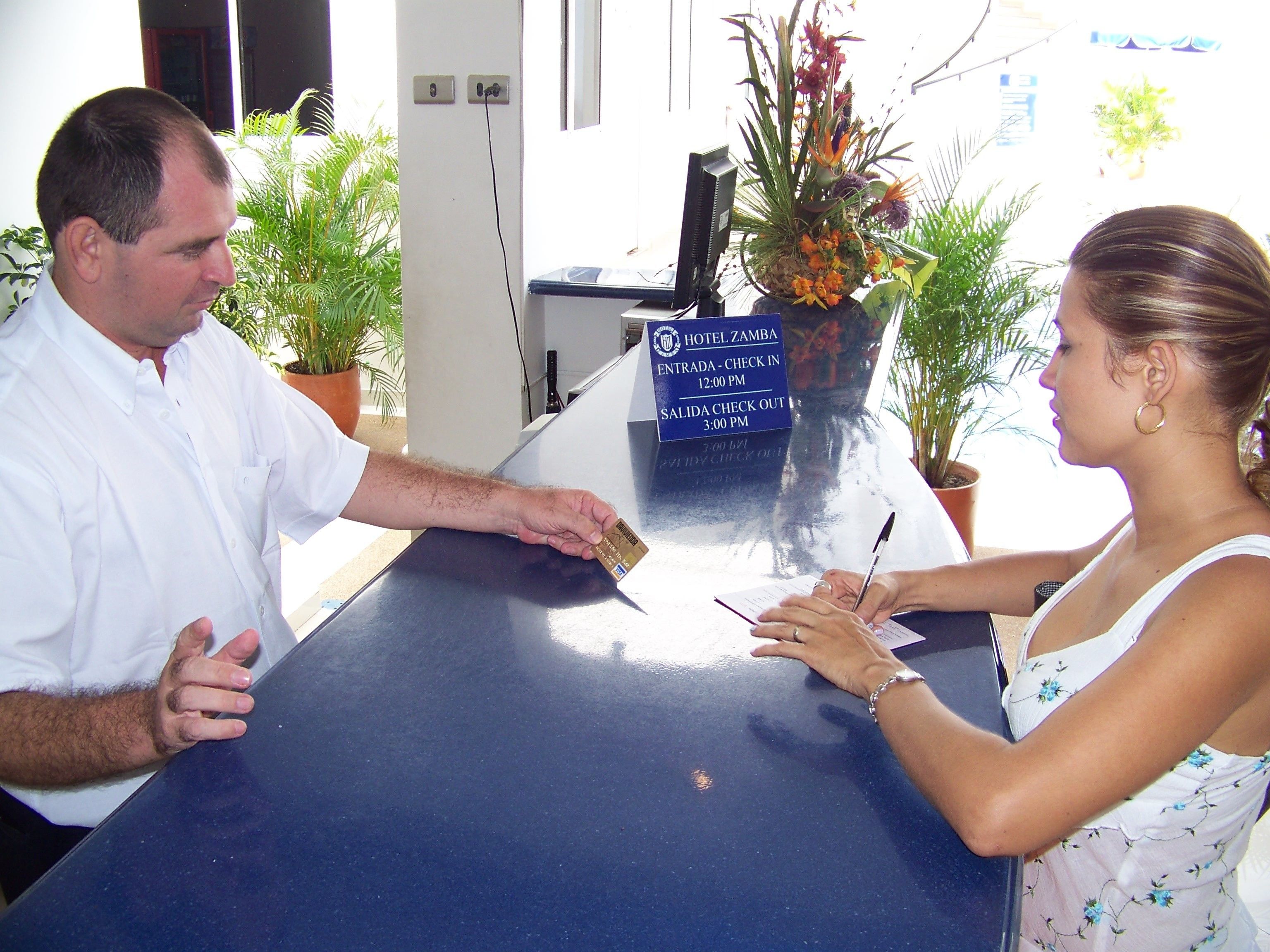 A hotel reception desk with a sign indicating check-in and check-out times.