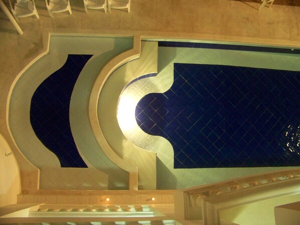 Un espace piscine agrémenté de motifs géométriques en mosaïque et d’un luminaire central.