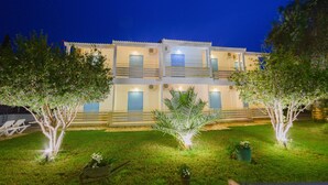 A two-story building with a balcony on the upper floor, surrounded by a well-maintained lawn and trees. - Olive Grove Resort (Corfu)