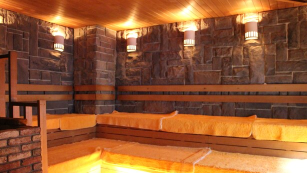 A stone-walled room with benches and wall-mounted lights. - Sauna & Capsule Hokuoh - Cators to Men (Tokyo)
