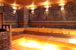 A stone-walled room with benches and wall-mounted lights. - Sauna & Capsule Hokuoh - Cators to Men (Tokyo)