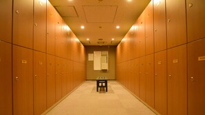 A row of wooden lockers with a small table in the center of a hallway. - Sauna & Capsule Hokuoh - Cators to Men (Tokyo)