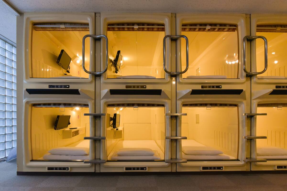 A row of bunk beds in a train car with individual compartments, each with a small window and a handle.