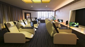 A hotel room with a large window, multiple reclining chairs, a flat-screen TV, and a small table with a remote control. - Sauna & Capsule Hokuoh - Cators to Men (Tokyo)