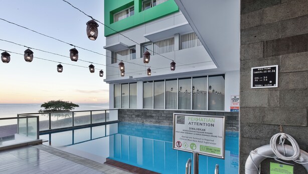 Un edificio moderno con area piscina, un cartello che indica la presenza di un bagnino e un salvagente appeso al muro.