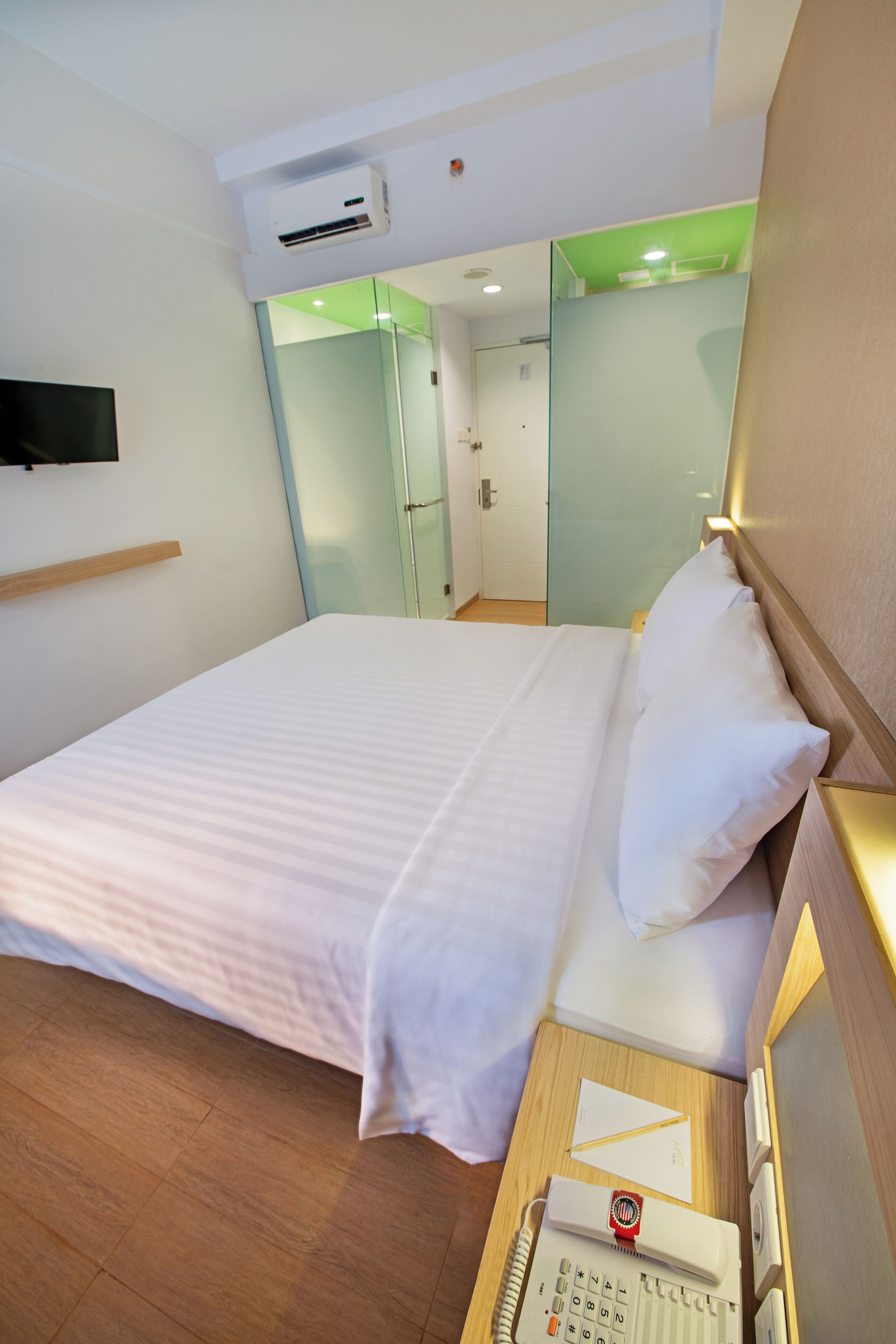 Une chambre d’hôtel équipée d’un lit, d’un téléphone sur la table de chevet et d’un téléviseur fixé au mur.