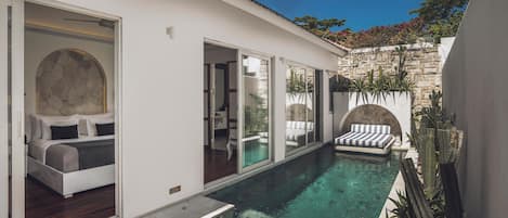 Una casa moderna con piscina, un dormitorio con cama grande y un área de patio.
