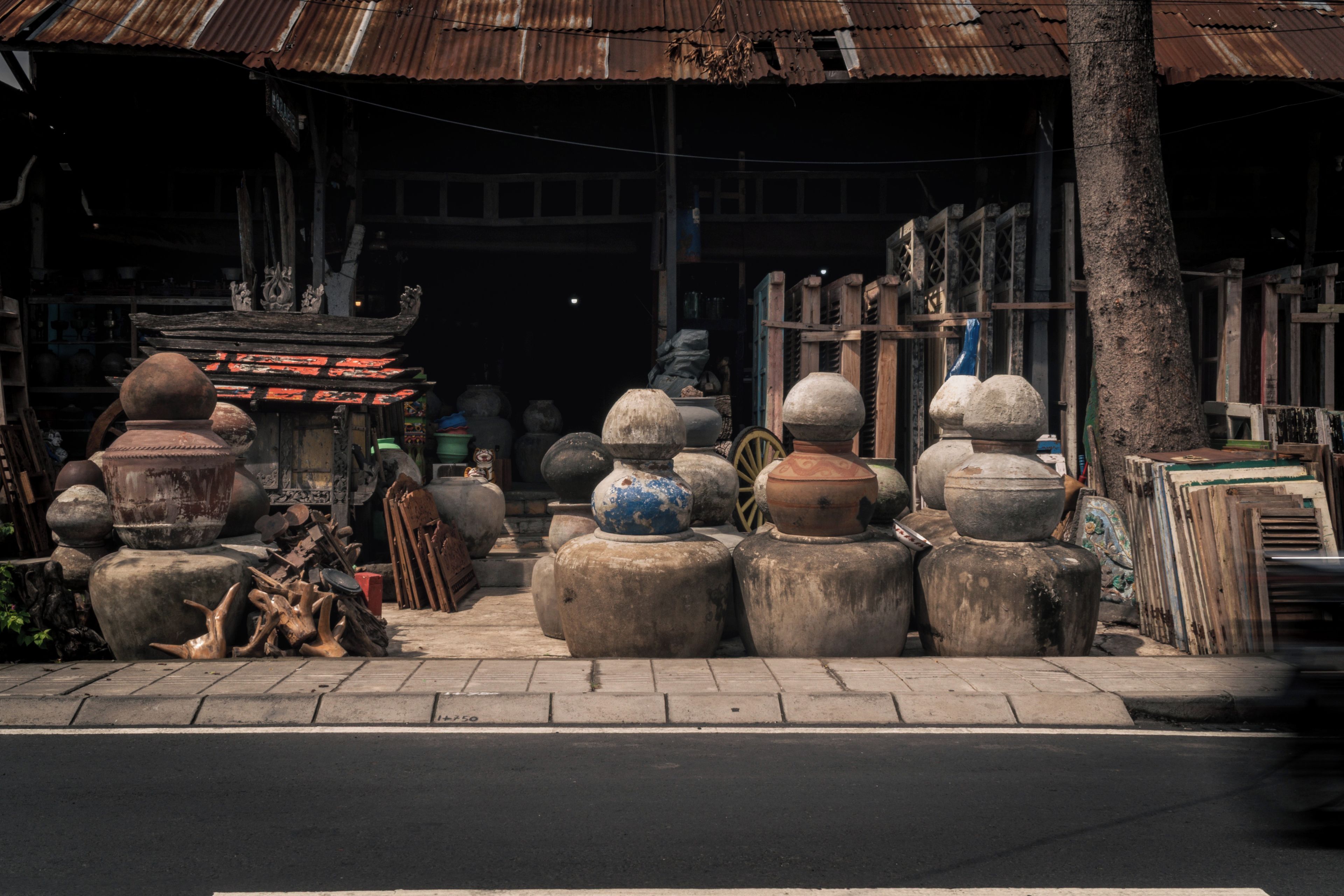 Une rangée de grands objets ronds, ressemblant à des pierres, se trouve à l’extérieur d’un bâtiment dont le toit est fait de tôle ondulée.