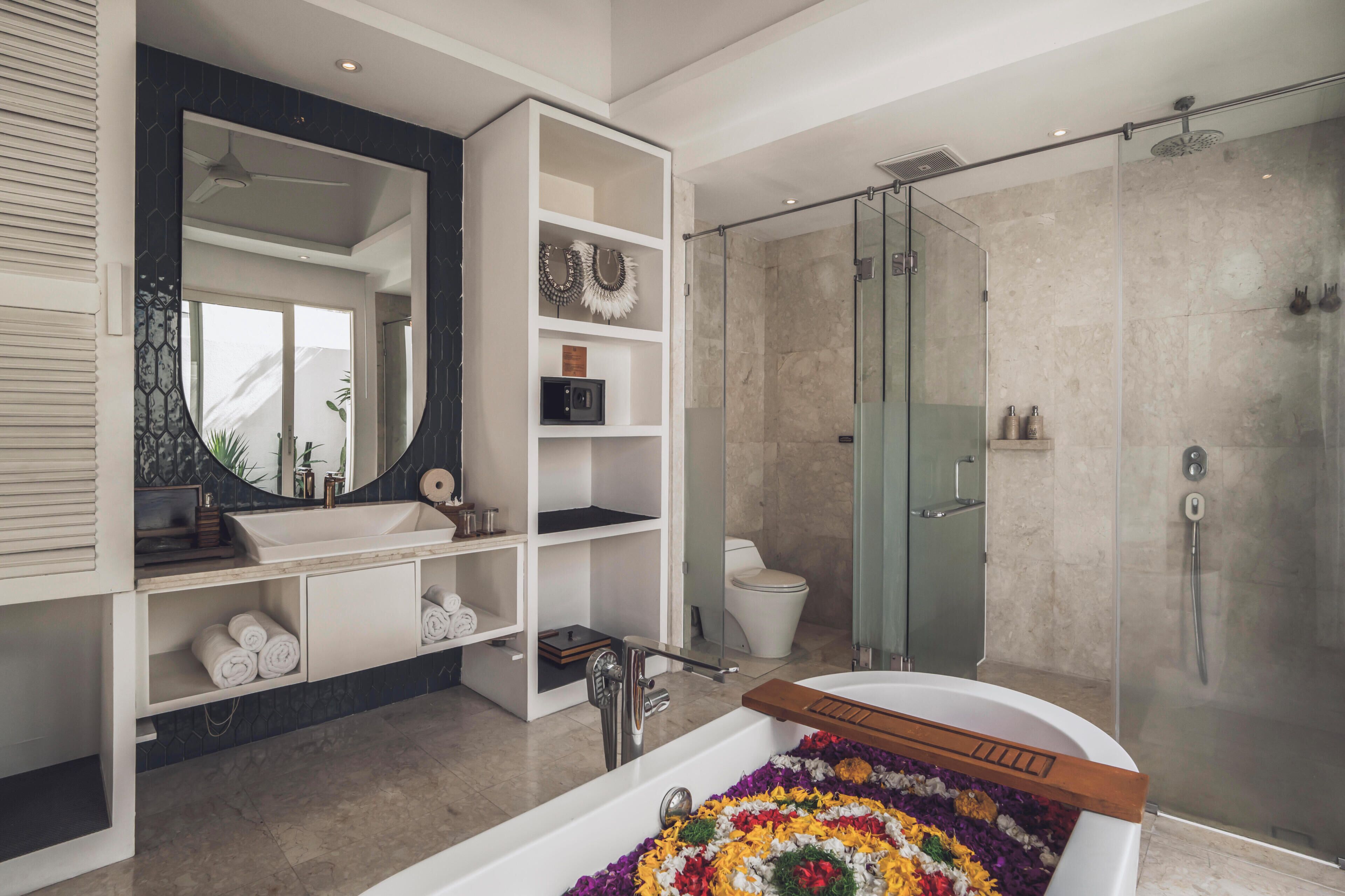 A modern bathroom with a freestanding bathtub, a glass-enclosed shower, and a vanity with built-in shelves.