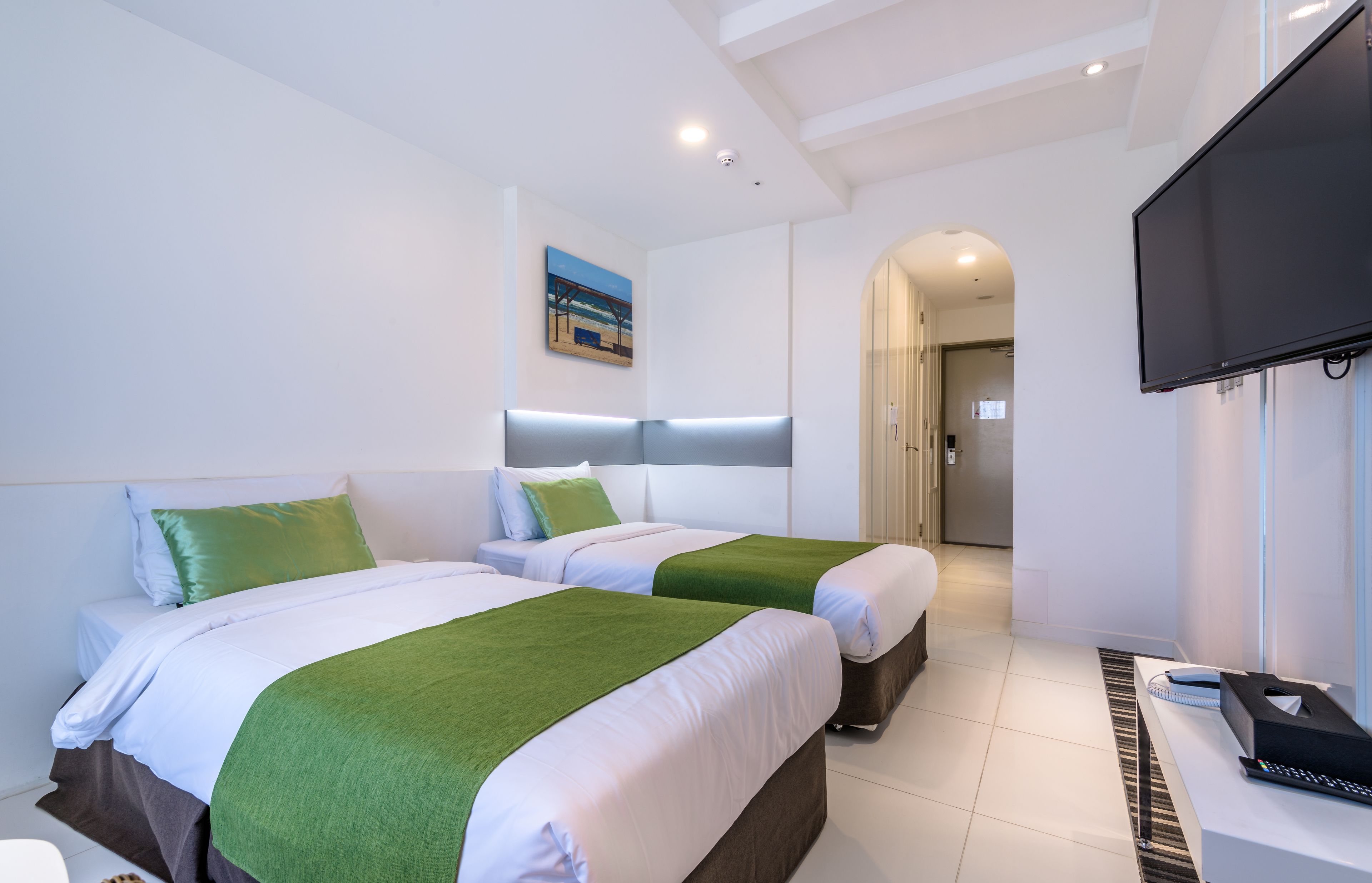 A hotel room with two beds, a flat-screen TV, a desk with a chair, and a painting on the wall.