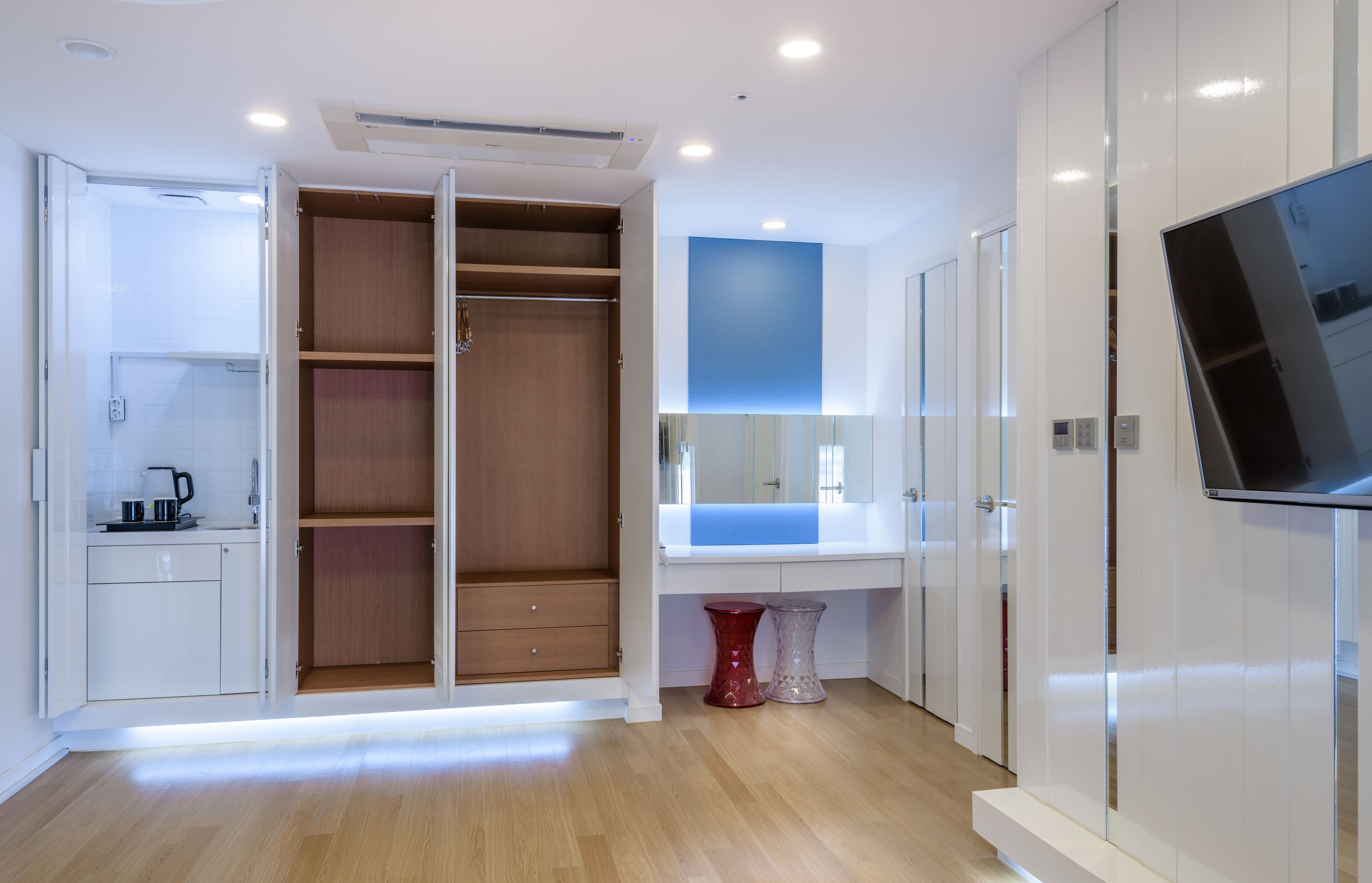 Ein modernes Badezimmer mit Dusche, Waschtisch mit Spiegel und einem an der Wand befestigten Fernseher.
