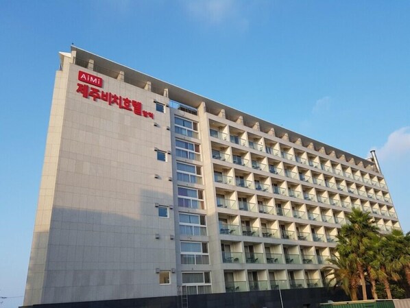 Un hotel de varios pisos con un diseño arquitectónico moderno, que presenta un llamativo logotipo de AiMi en la fachada.