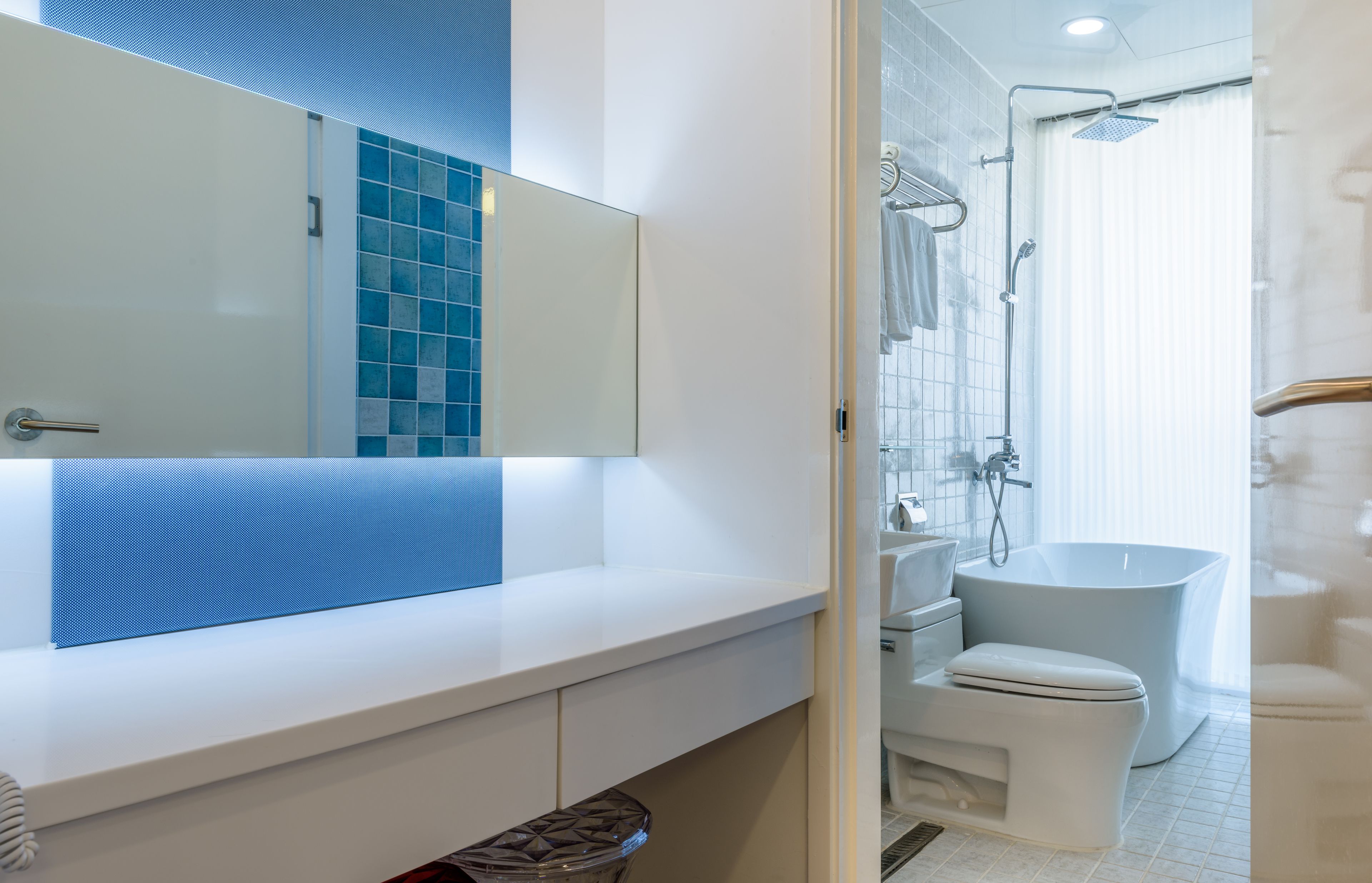 A modern bathroom with a white sink, mirror, and a freestanding bathtub.