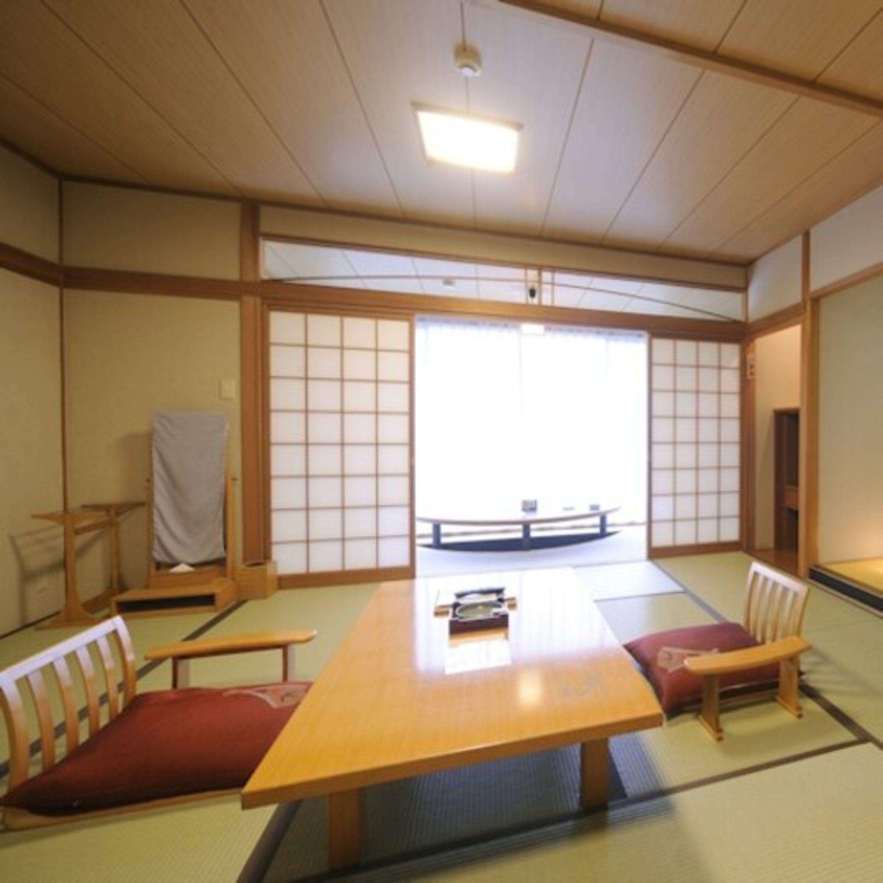 Une pièce de style japonais traditionnel, avec un sol recouvert de tatamis, une table basse et des meubles en bois.