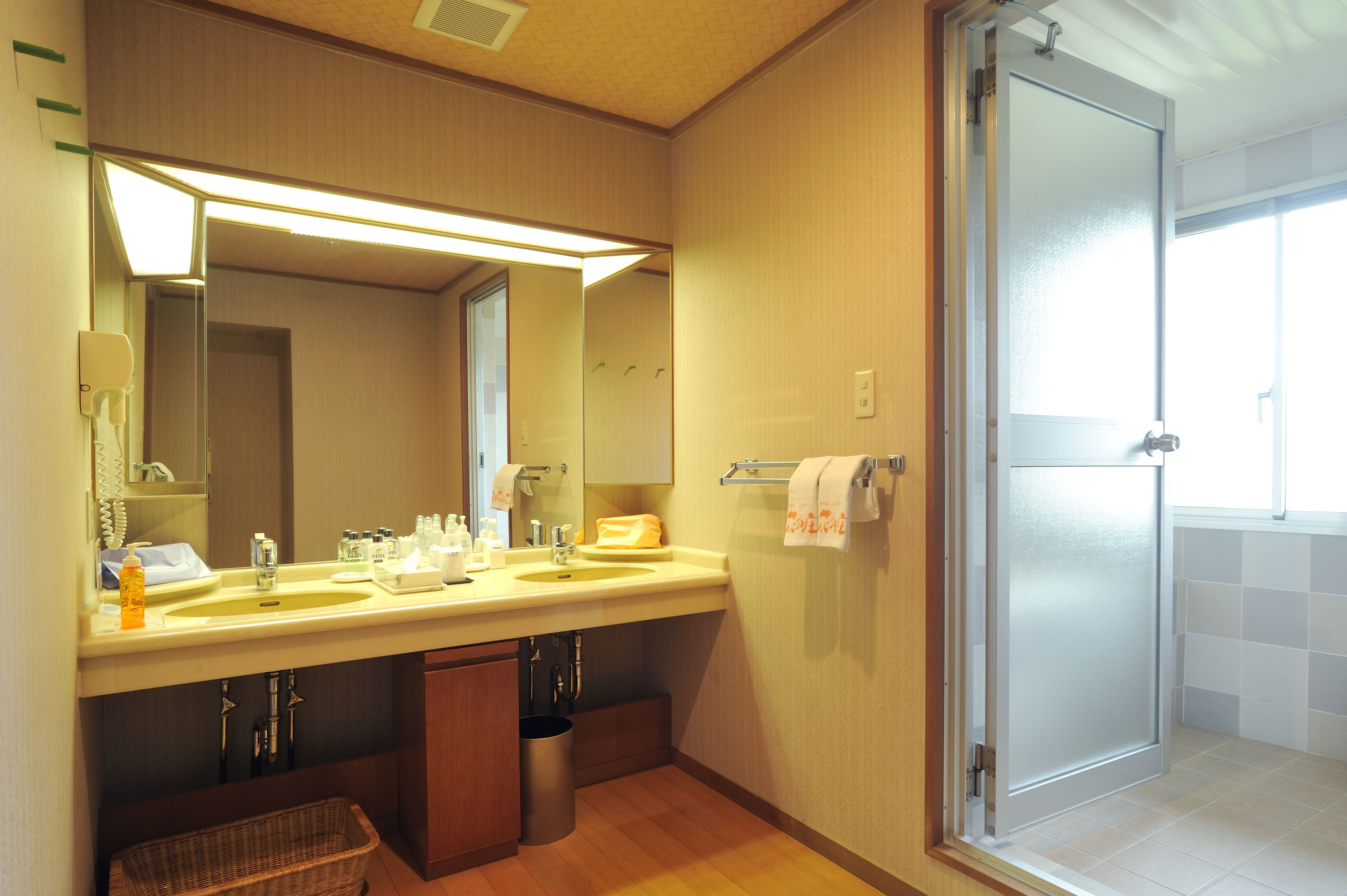 A bathroom with a double sink, mirror, towel rack, and a glass shower door.