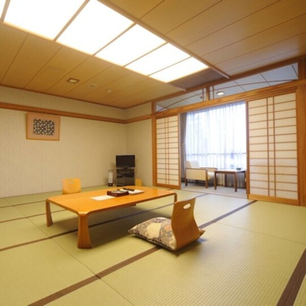 Una habitación japonesa tradicional con suelo de tatami, una mesa baja y puertas correderas.