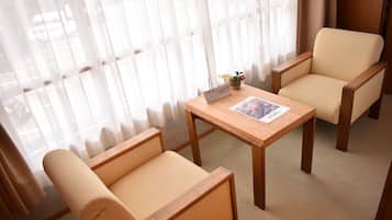 Una habitación con una mesa de madera y dos sillones color beige.