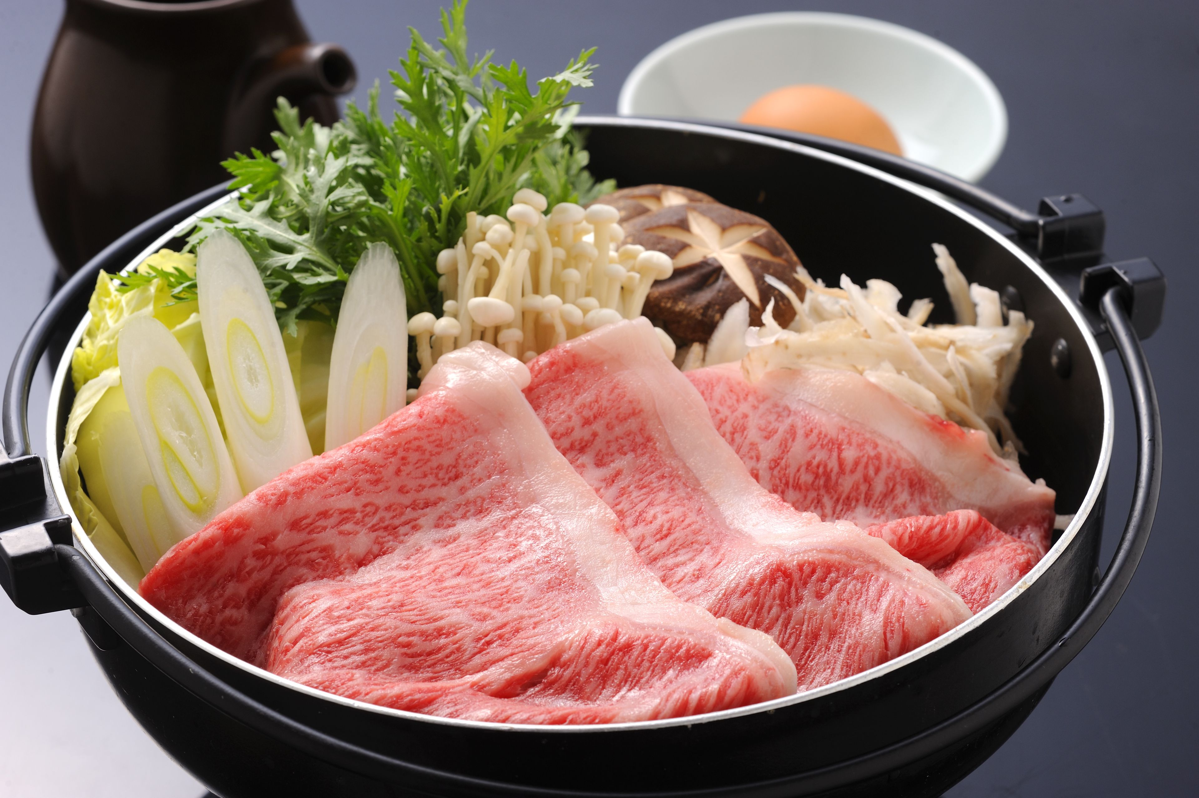 A pot with raw meat, vegetables, and mushrooms.
