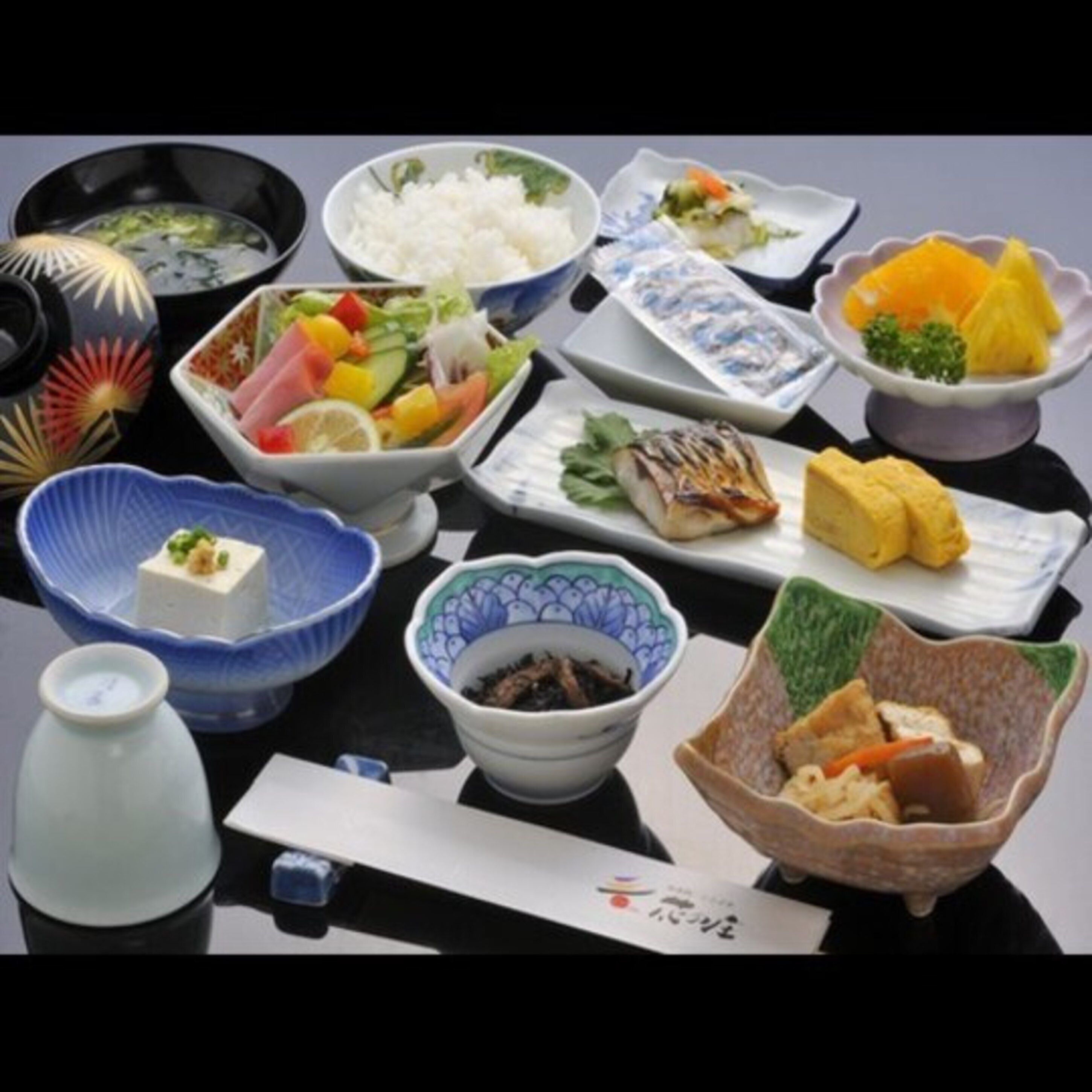Ein Tisch mit verschiedenen japanischen Gerichten, darunter Sushi, Reis und eingelegtes Gemüse.
