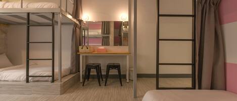 A bunk bed room with a desk, two stools, and a mirror.