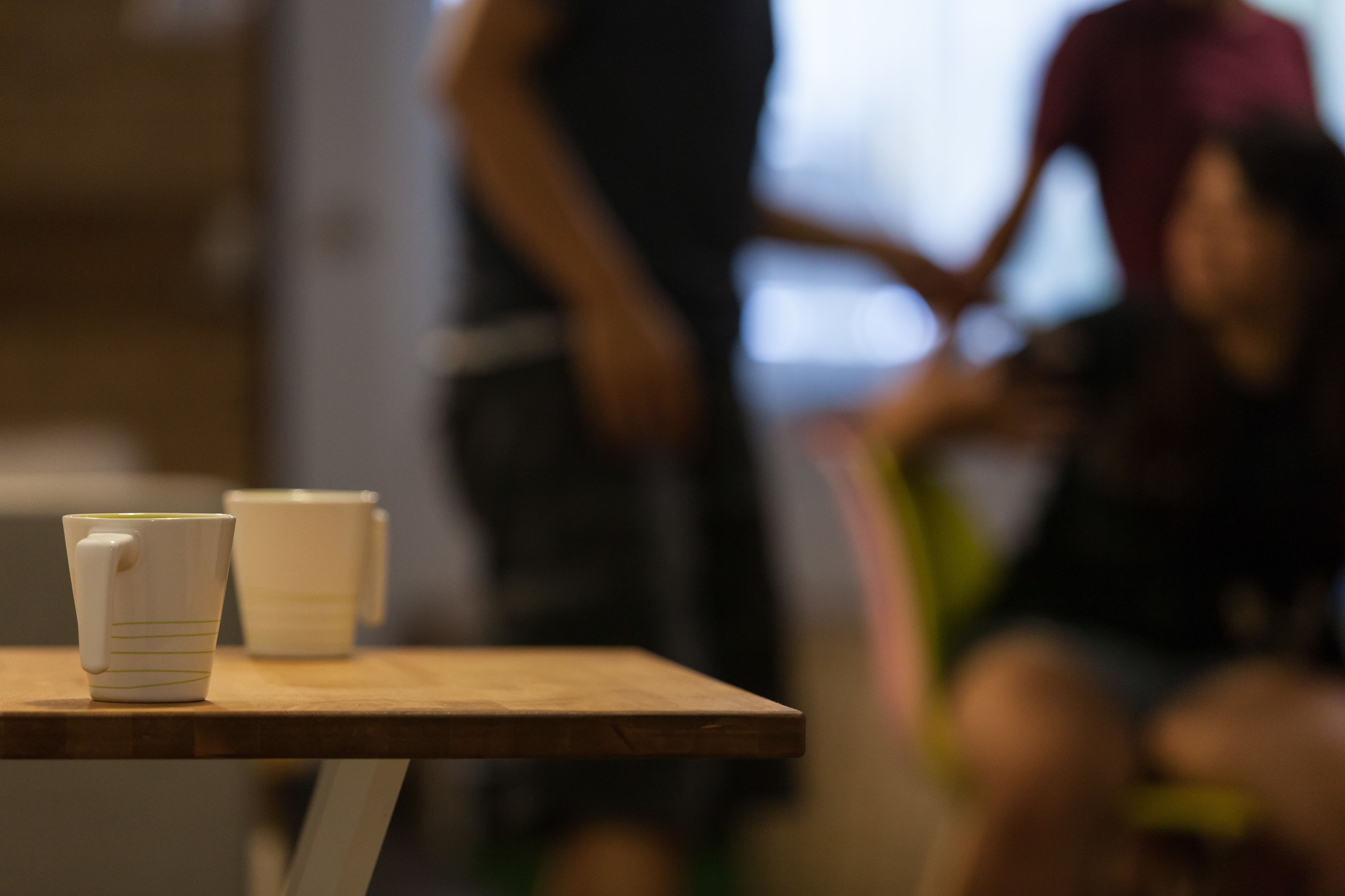 Una mesa con dos tazas blancas y superficie de madera.