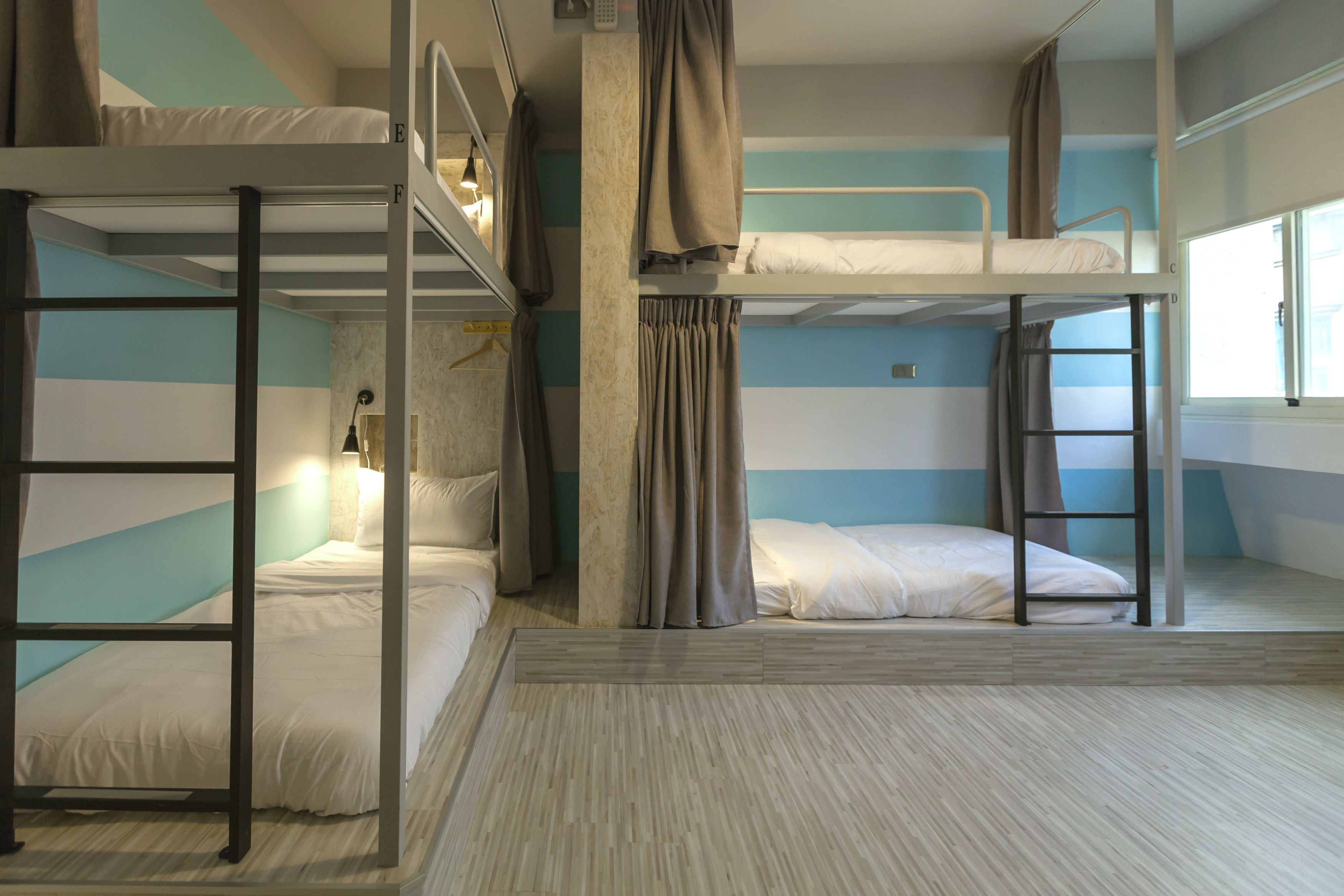 A bunk bed room with a window, curtains, and a lamp.
