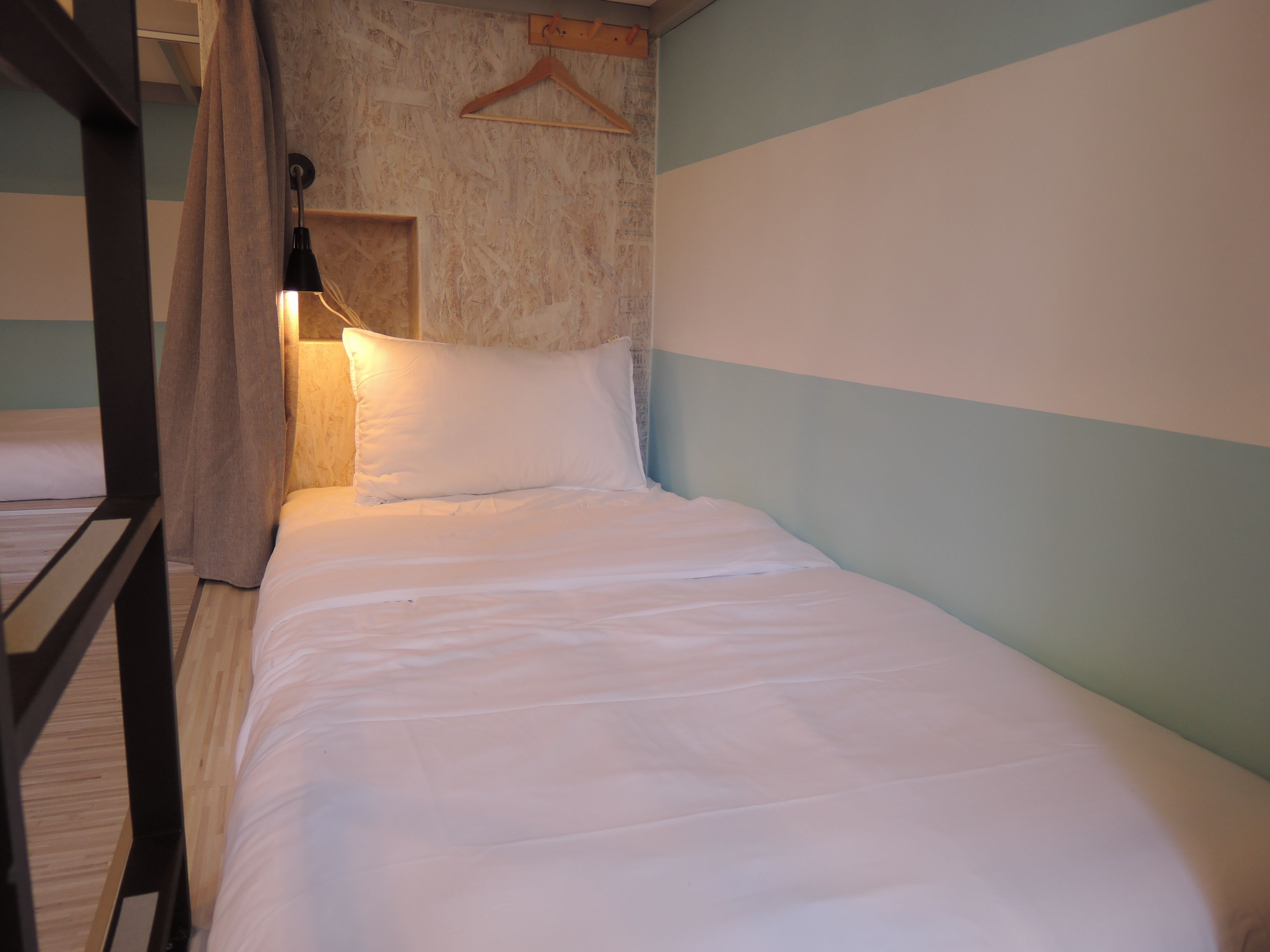 A bunk bed with a hanging light fixture and a wooden hanger on the wall.