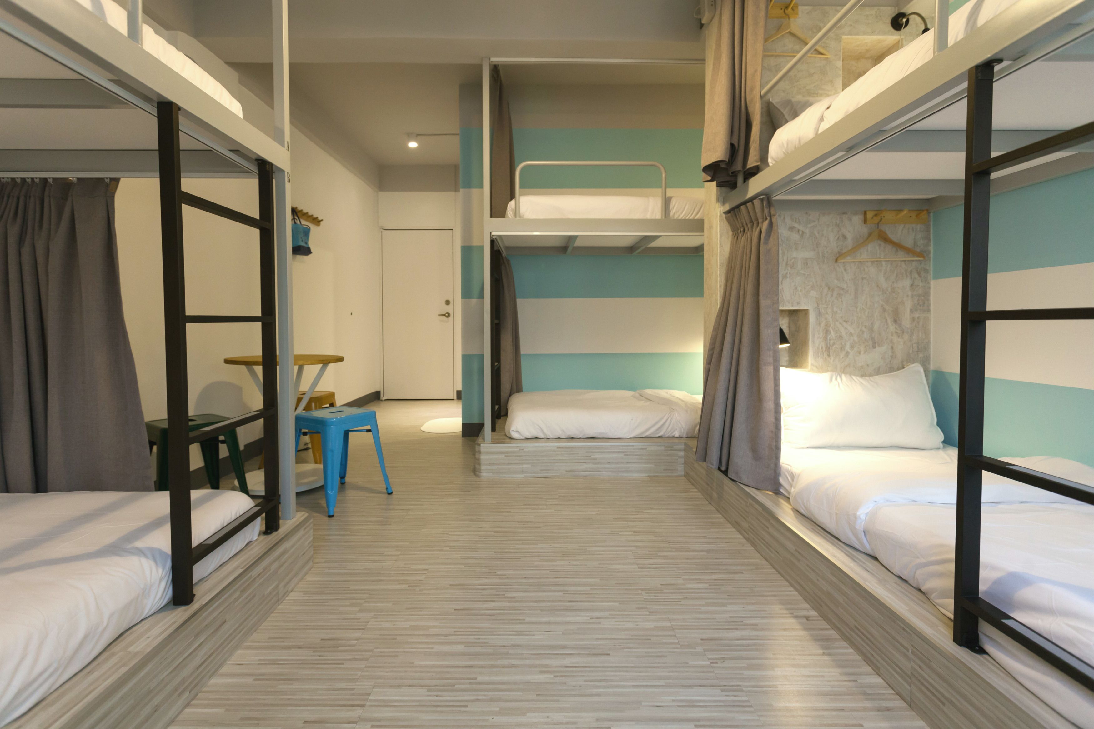 A room with bunk beds, a small table, and a chair.