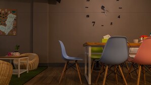 Una habitación acogedora con una mesa de madera, sillas de mimbre, un reloj en la pared y un mapa.
