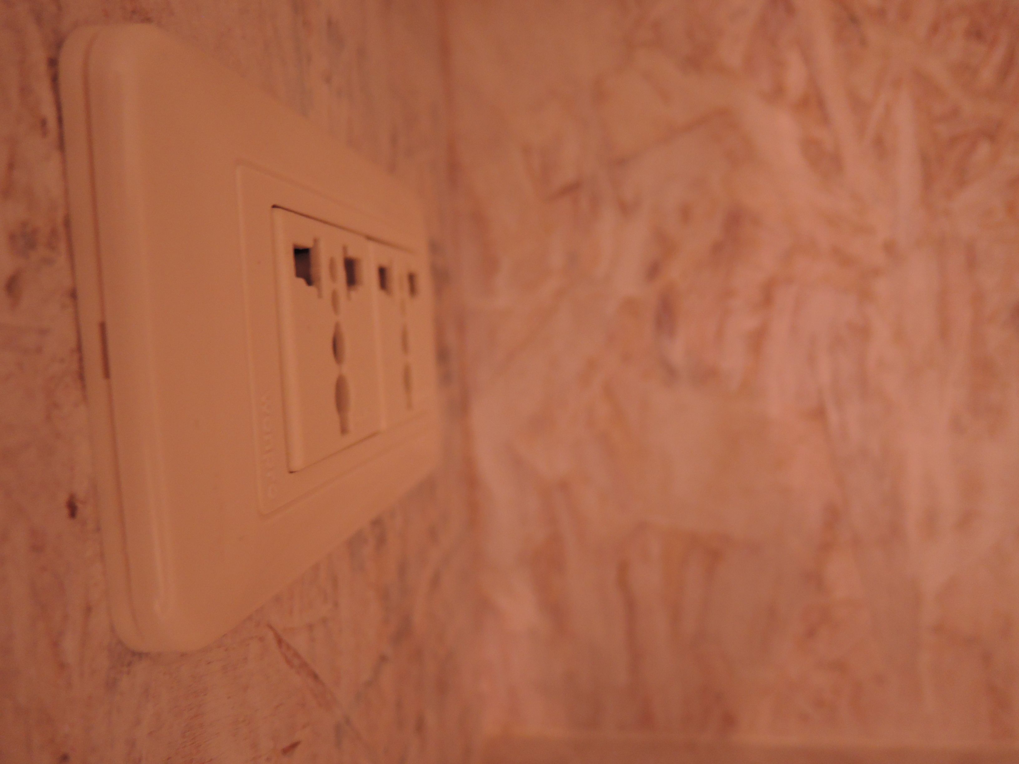 Un enchufe blanco en una pared con textura.
