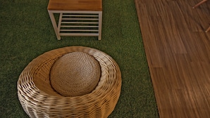 Una habitación con una mesa de madera, una silla de mimbre y una pequeña planta en maceta.