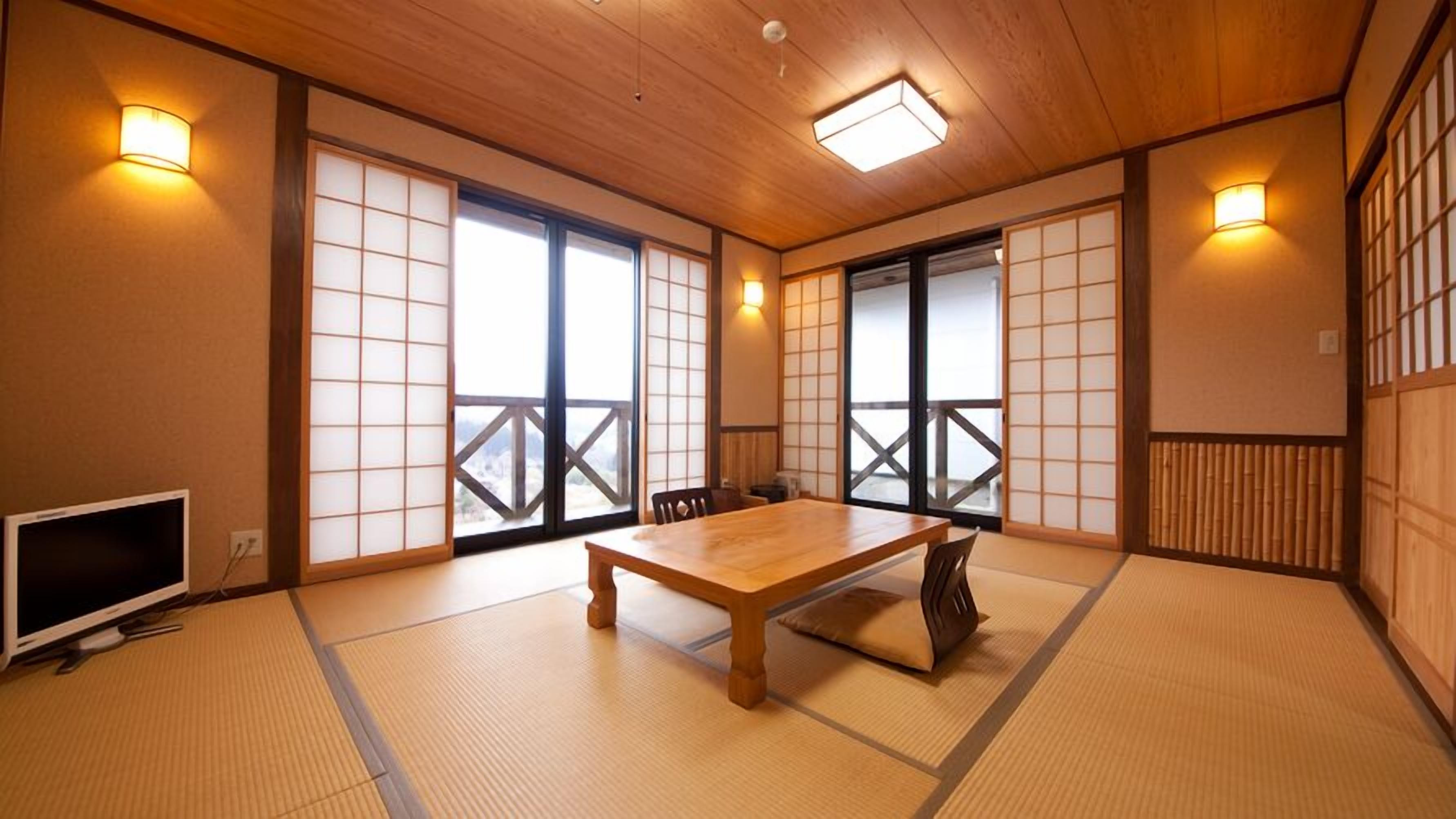 Une pièce de style japonais traditionnel, avec un sol recouvert de tatamis, une table en bois, des portes coulissantes et un téléviseur.