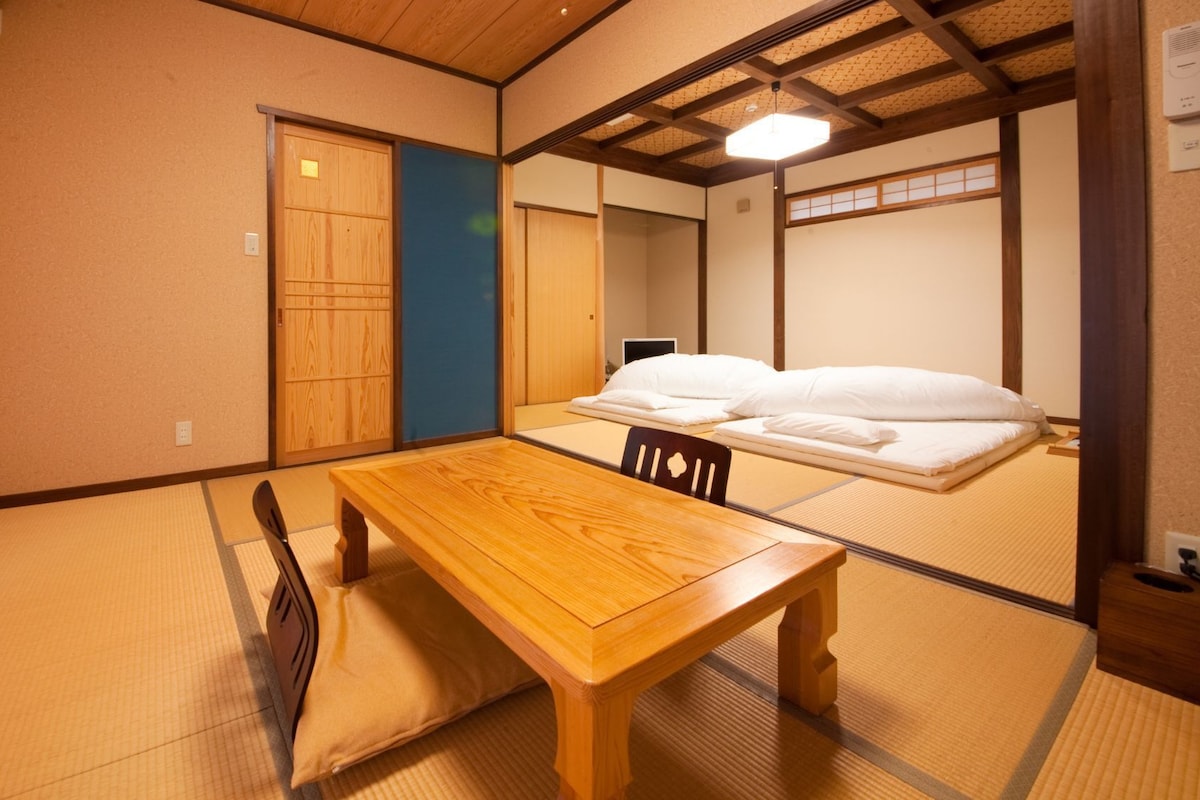 A traditional Japanese room with tatami flooring, a wooden table, and a futon bed.