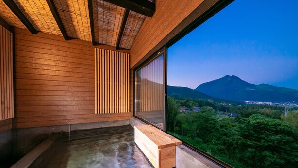 Un interior de madera con una bañera de hidromasaje y un ventanal con vistas a un paisaje montañoso.