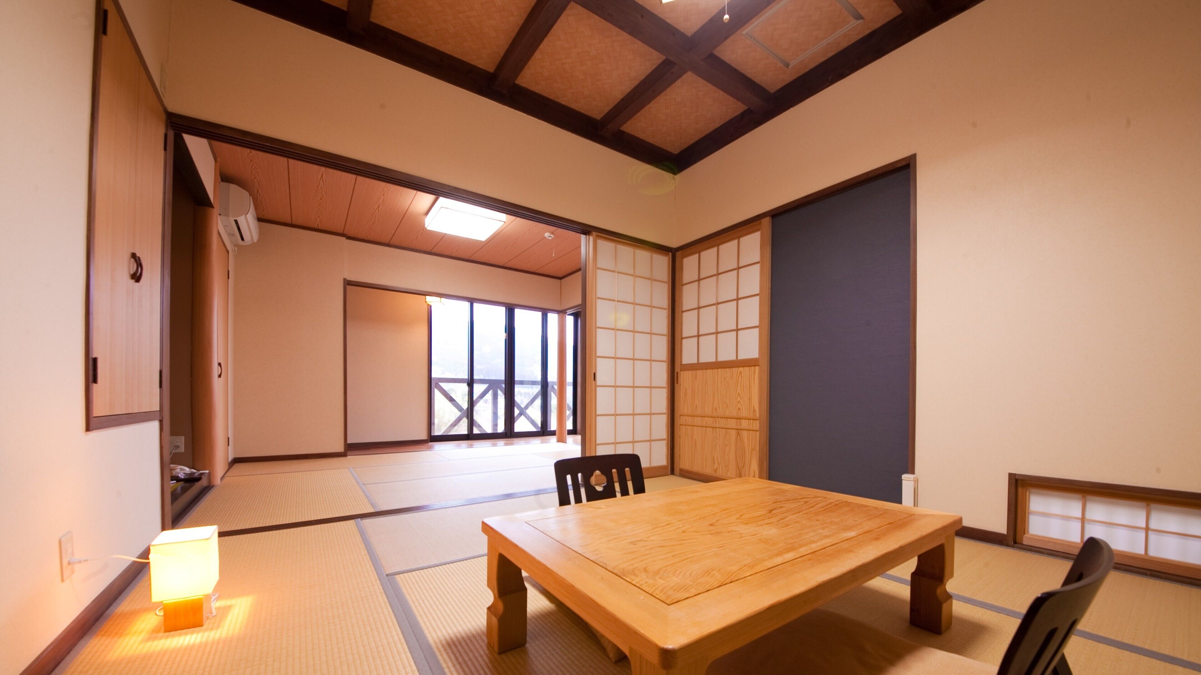 Een traditionele Japanse kamer met tatami vloerbedekking, een houten tafel en schuifdeuren.