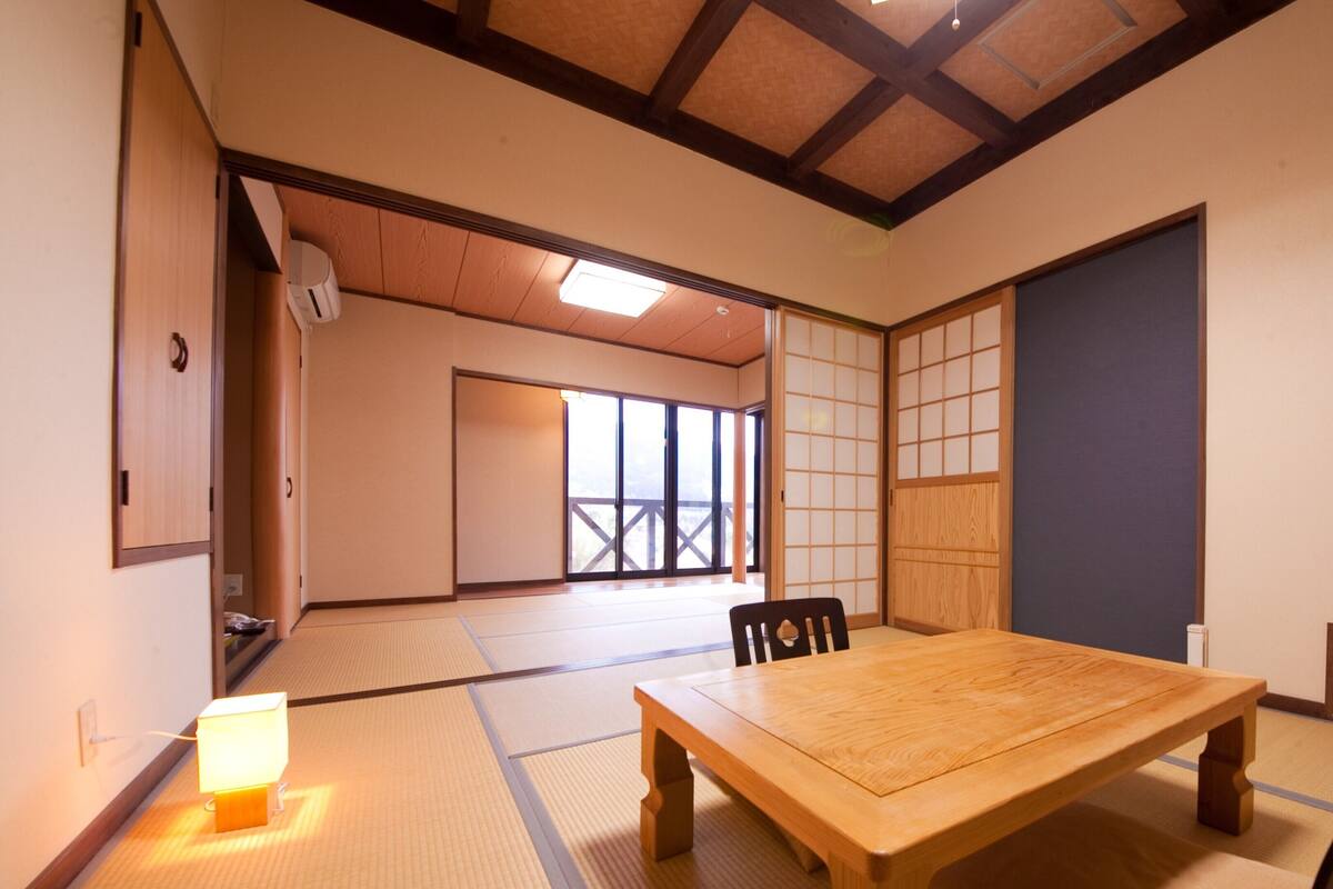 Een traditionele Japanse kamer met tatami vloerbedekking, een houten tafel en schuifdeuren.