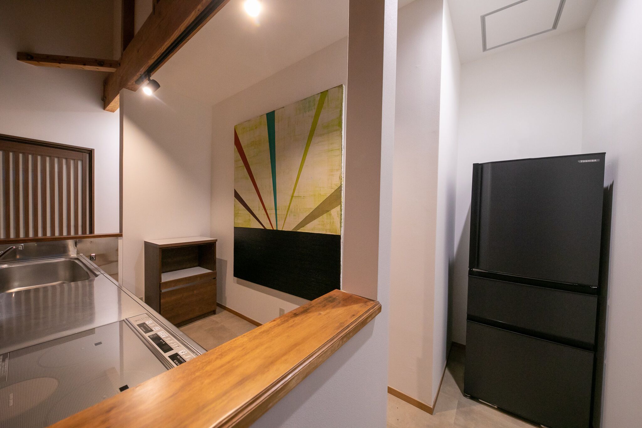 A modern kitchen with a stainless steel sink, a black refrigerator, and a wooden countertop.