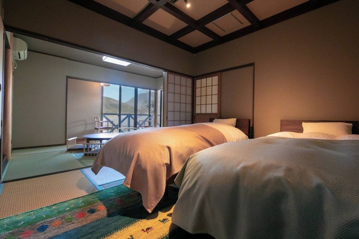 Een traditionele Japanse kamer met tatami vloeren, twee bedden, een schuifdeur en uitzicht op een berg.
