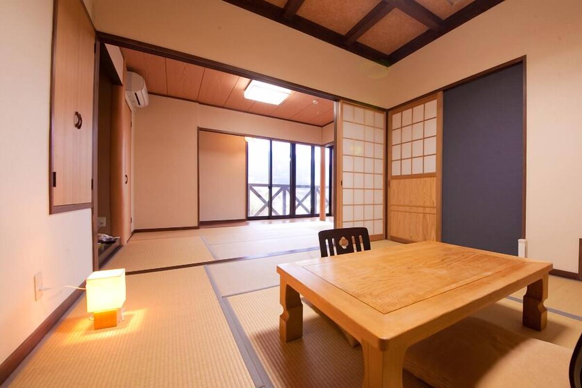 Une pièce de style japonais traditionnel, avec un sol recouvert de tatamis, une table en bois et des portes coulissantes.