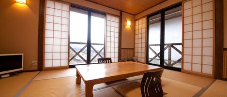 A traditional Japanese room with tatami flooring, a wooden table, and sliding doors.