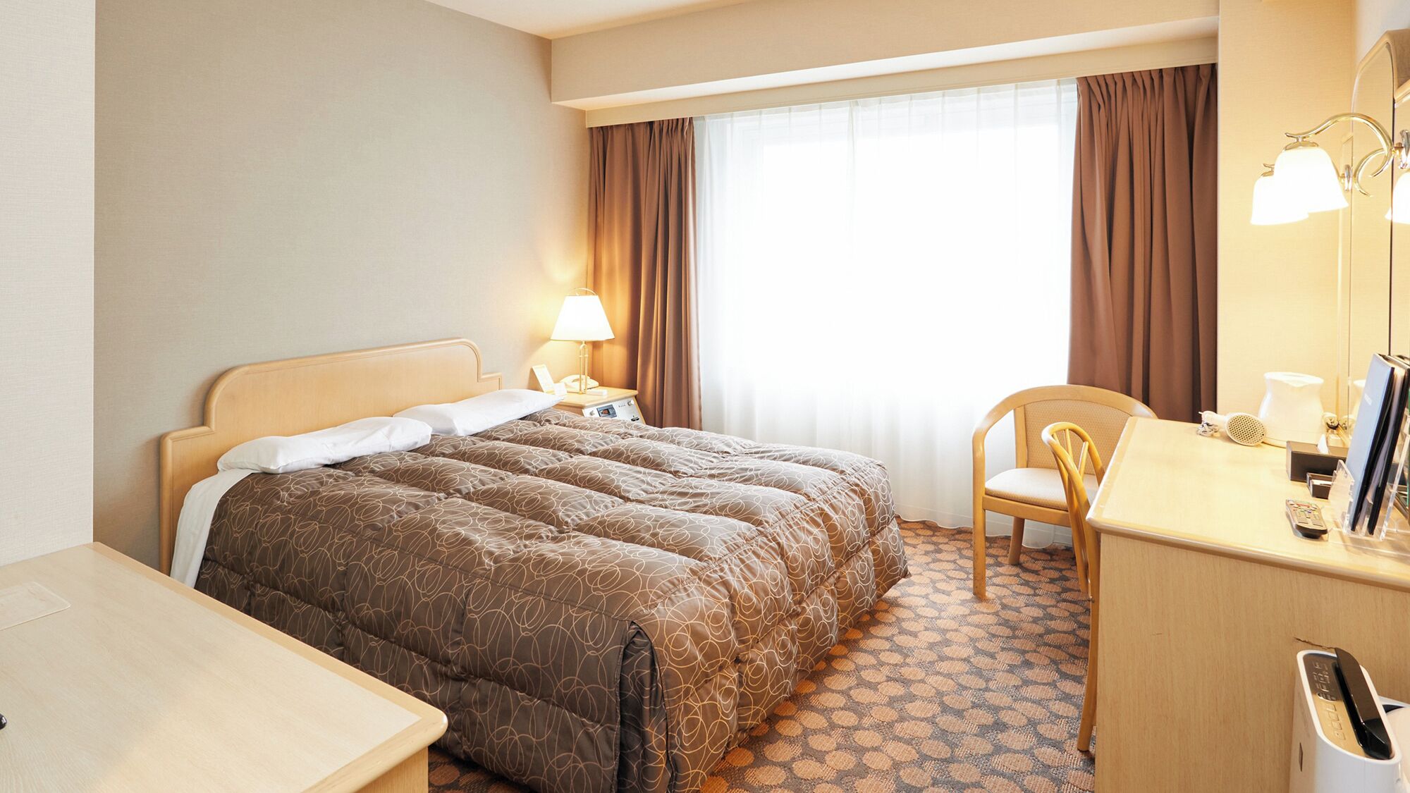Una habitación de hotel con una cama, un escritorio, una silla, una lámpara y una ventana con cortinas.