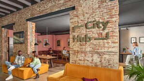 A modern lounge area with brick walls, orange seating, and a 'City Hub' sign. - CityHub Amsterdam (Amsterdam)