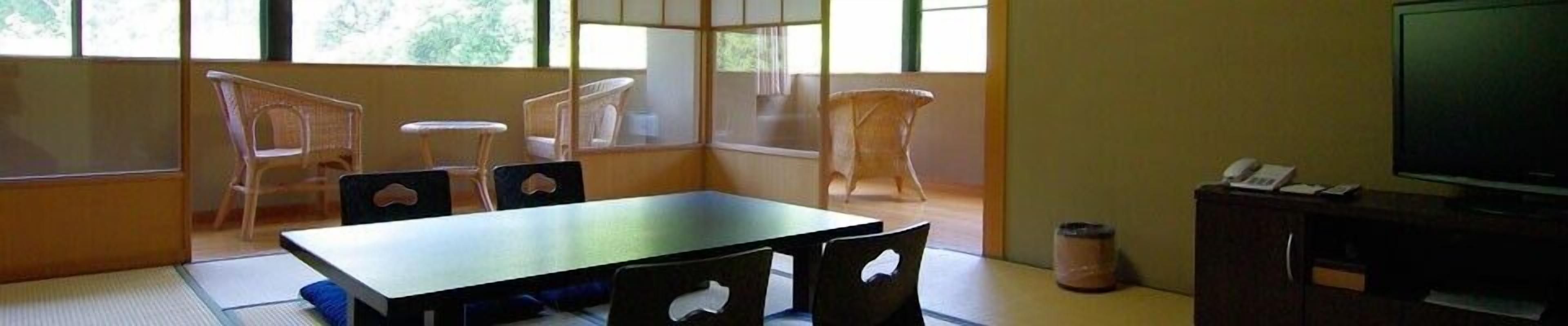 A room with a wooden table, four chairs, a television, and a cabinet.