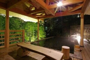 Una terraza de madera con un banco y un jacuzzi.