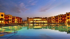 A hotel with a swimming pool, reflecting the buildings and sky.