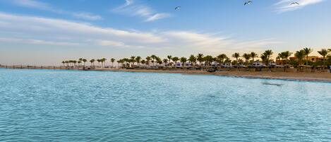 Pantai pribadi, pasir putih, kursi berjemur, dan payung pantai
