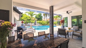 A modern outdoor dining area with a pool, outdoor furniture, and a grill. - Pattaya Hill, Near the City and Beach (Pattaya)